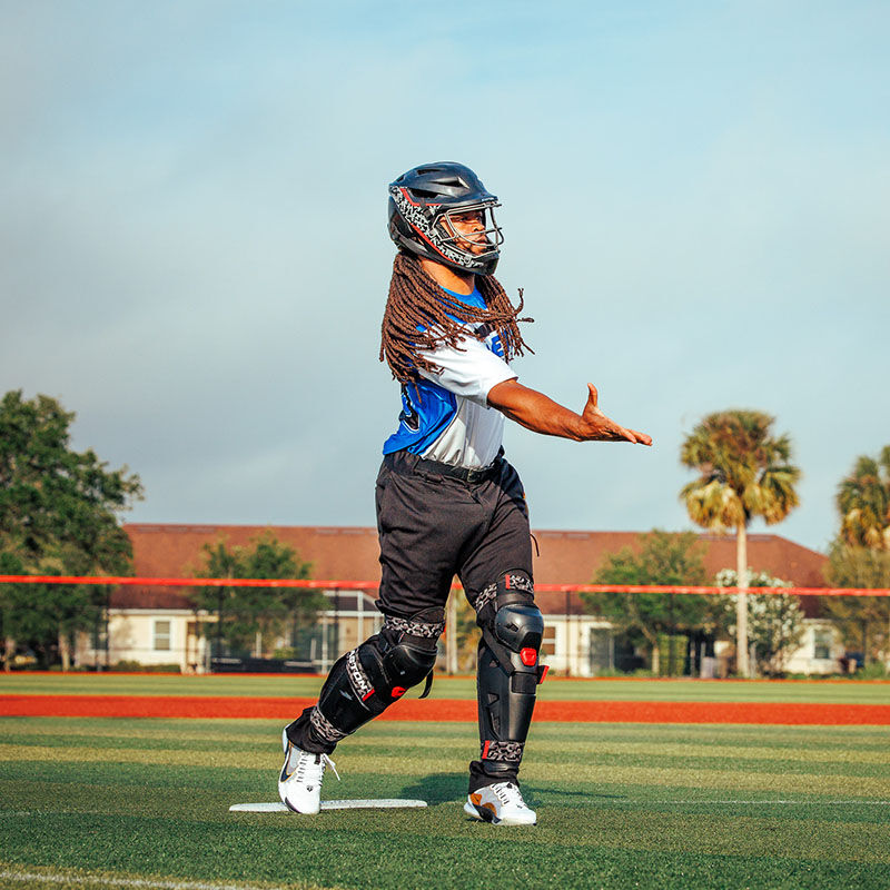 A player pitching a ball wearing a Easton Hellcat Mojo slowpitch fielding helmet and leg guards - SKU: HELMOSPH loading=