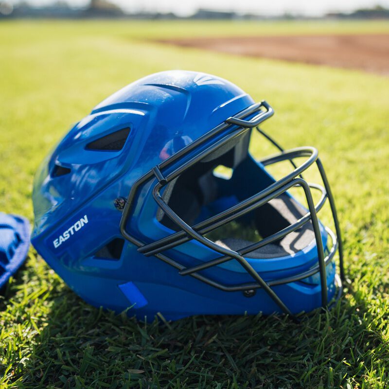 A royal Easton Easton Black Magic 3.0 youth catcher's helmet on grass