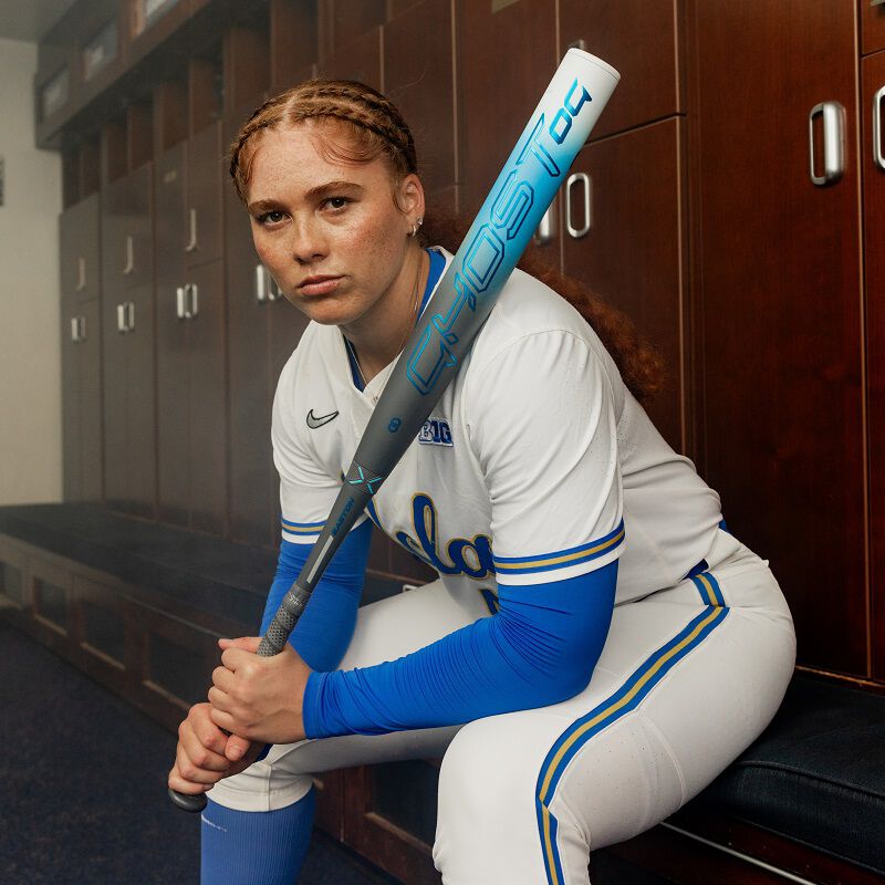 Picture of a UCLA fastpitch player sitting in a locker room with 2025 Easton Ghost OG fastpitch bat on her shoulder