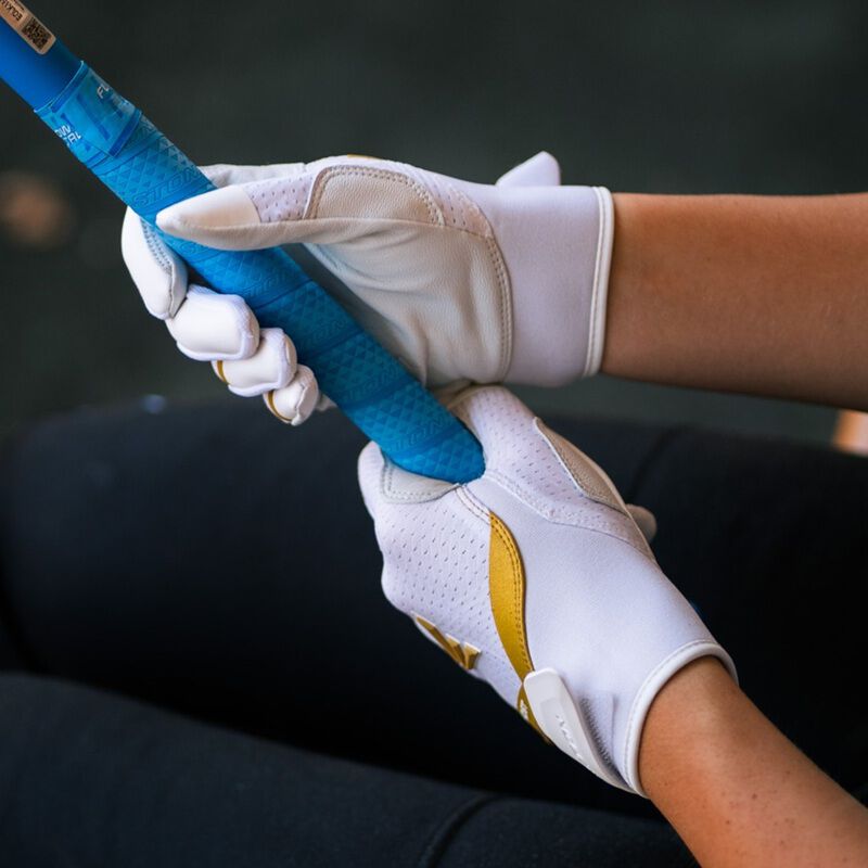 Picture of a player wearing a pair of white Ghost Ethos Snowstorm fastpitch batting gloves holding a bat