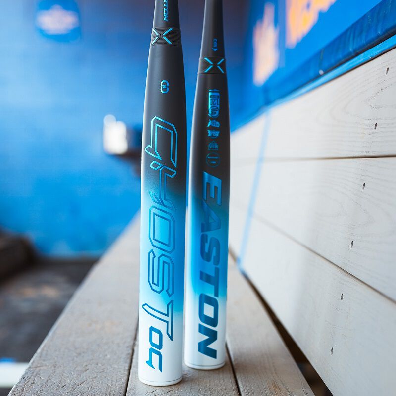 Picture of two 2025 Easton Ghost OG fastpitch bats stood up on a bench in a dugout