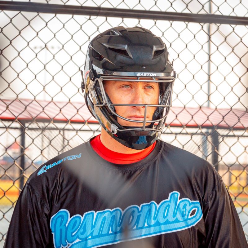 A player wearing a black Easton Hellcat slowpitch helmet in a dugout - SKU: EHCATH loading=