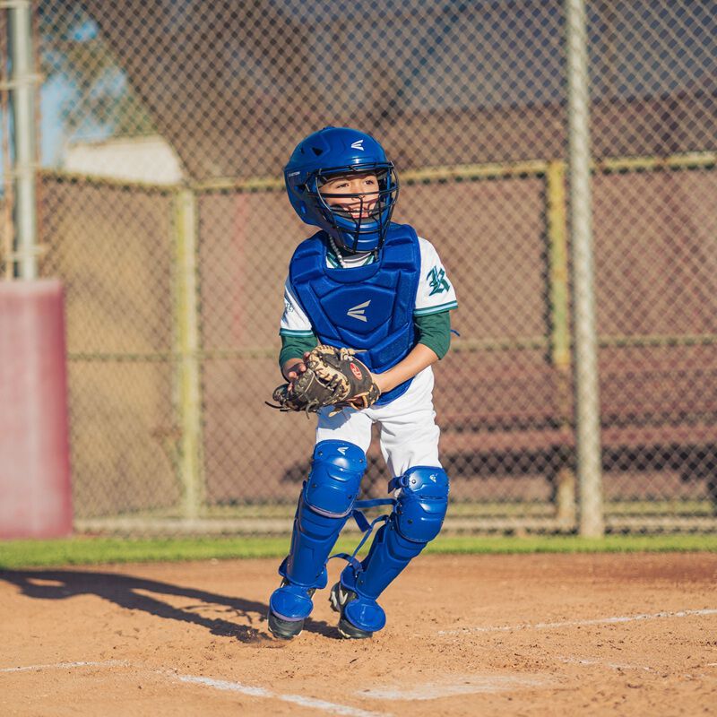A player getting ready to throw a ball wearing a royal Easton Black Magic 3.0 youth catcher's set