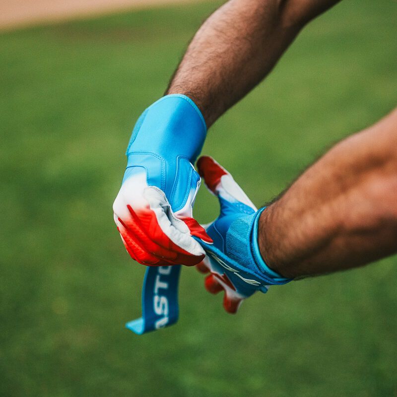 A player strapping the wrist of an Easton Walk-Off Ethos Locked-In Rocket Pop batting glove loading=