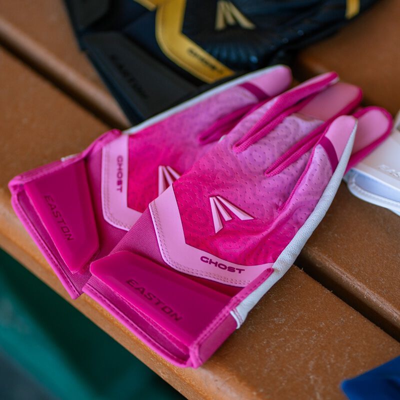 A pair of pink Ghost Ethos Strawberry Glow fastpitch batting gloves on a bench loading=