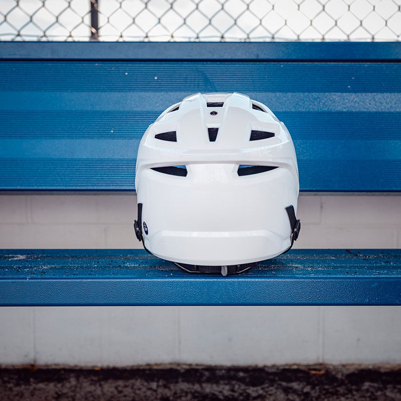 Back of a white Easton Hellcat slowpitch pitcher's helmet on a bench in the dugout - SKU: EHCATH