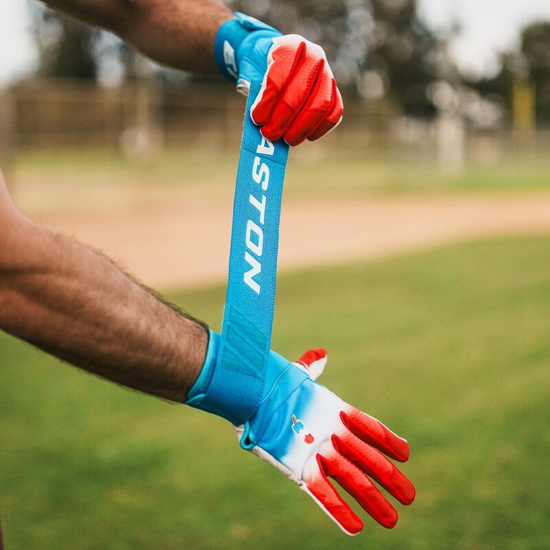 A player adjusting the long strap of an Easton Walk-Off Ethos Locked-In Rocket Pop batting glove