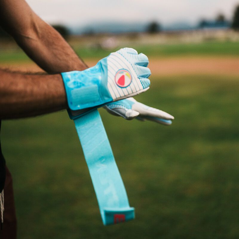 A player adjusting the long strap on an Easton Walk-Off Ethos Locked-In Pool Party batting glove loading=